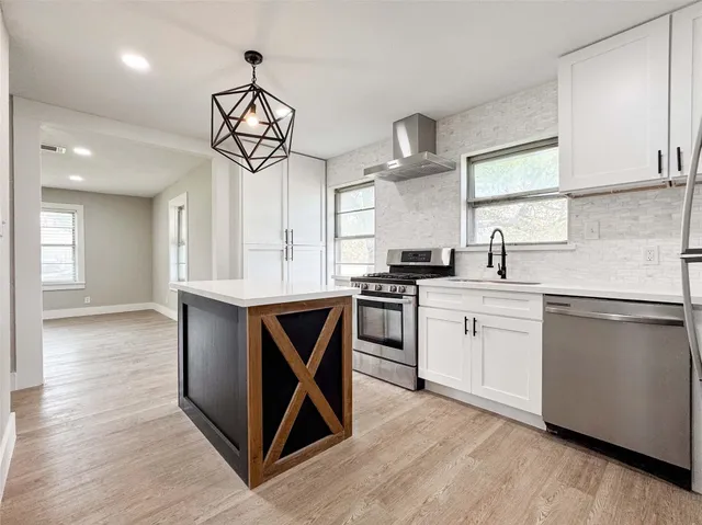 a kitchen with stainless steel appliances granite countertop a sink a stove a refrigerator and island with wooden floor