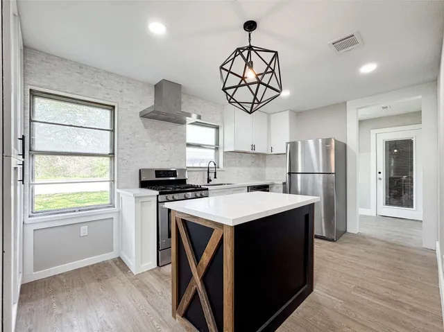 a kitchen with stainless steel appliances a stove a refrigerator and a sink with wooden floor