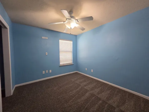 an empty room with window and chandelier fan