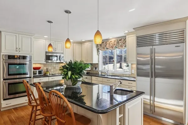 a kitchen with stainless steel appliances granite countertop a kitchen island a stove a table and chairs