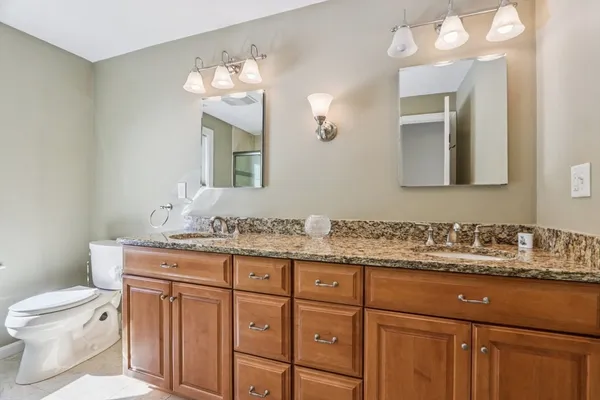 a bathroom with a granite countertop toilet sink and mirror