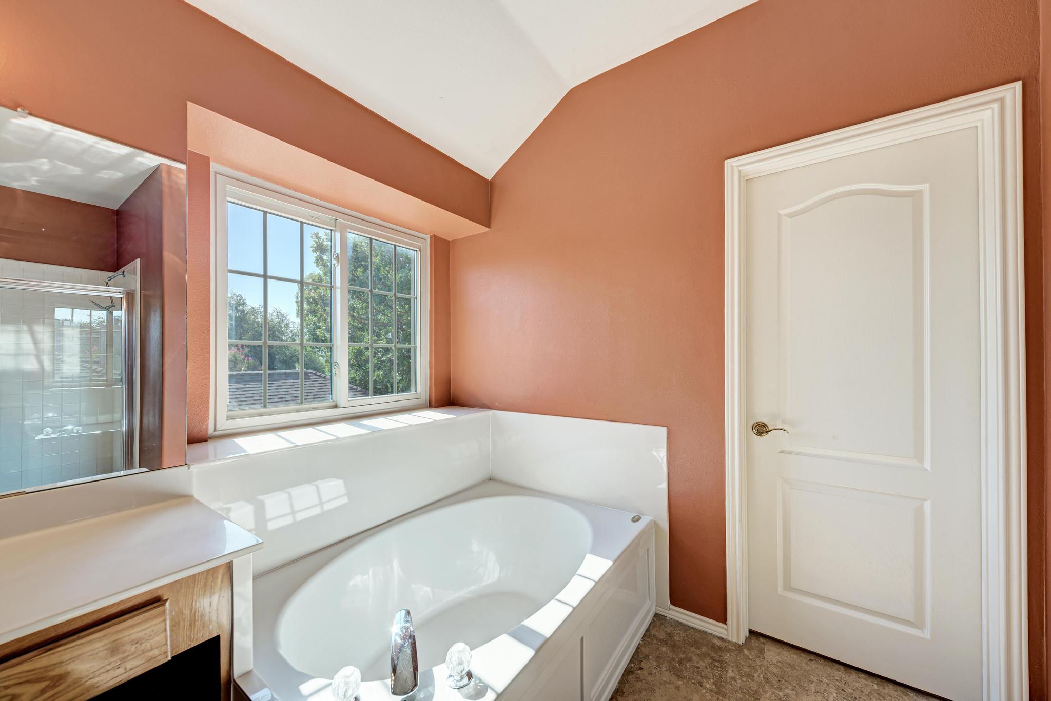 906 Antelope Ridge Cedar Park, TX 78613 - Photo 29 of 40 A deep soaking tub sits under sloped ceilings and a wide window with neighborhood views.
