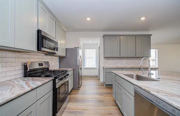 a kitchen with stainless steel appliances granite countertop a sink stove and cabinets