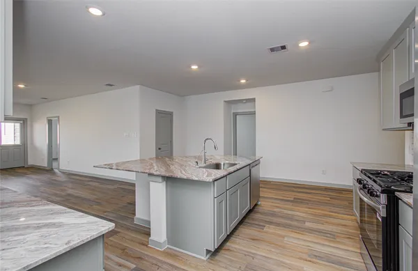 a kitchen with stainless steel appliances granite countertop a sink stove and wooden floor