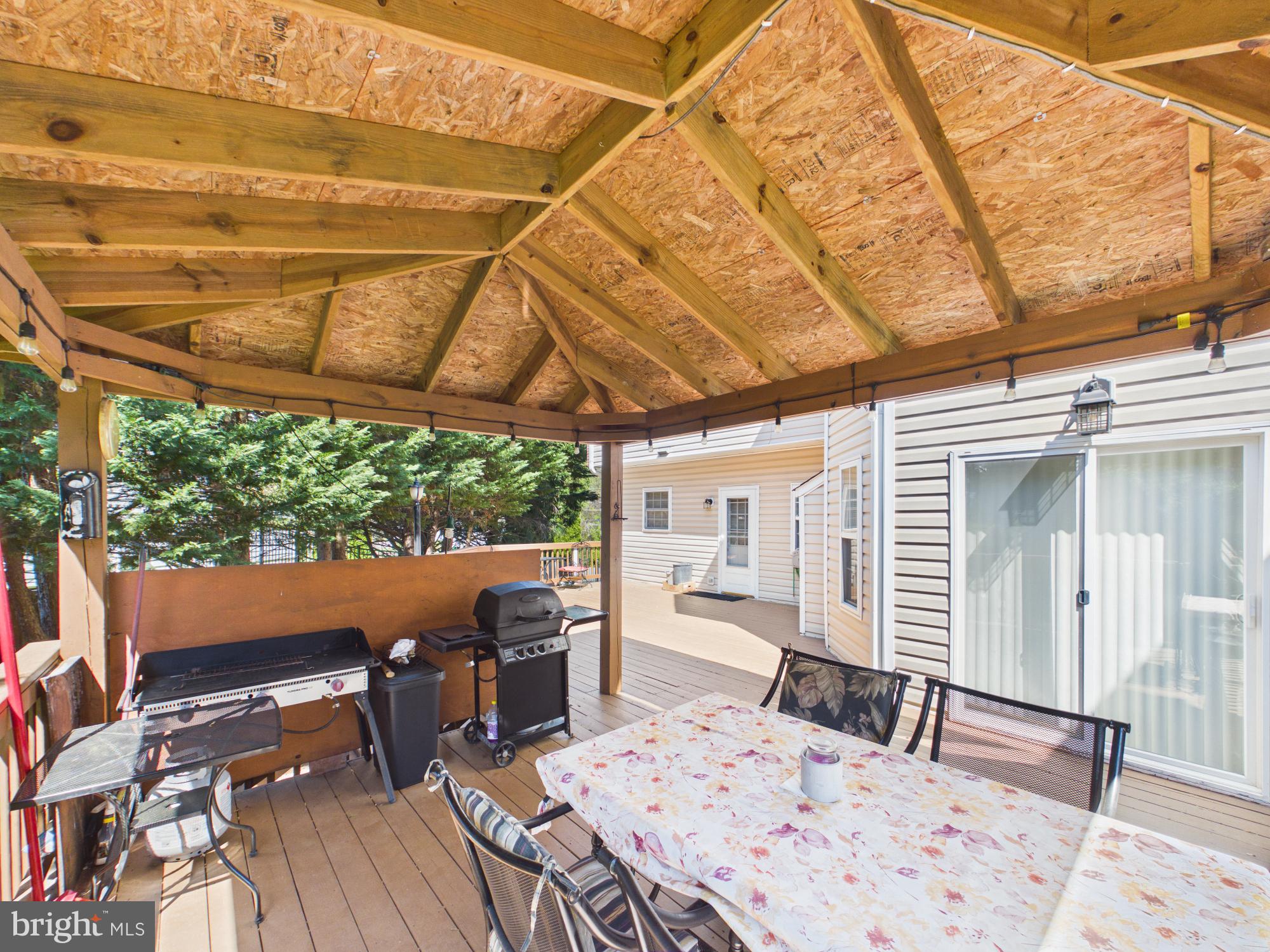 7801 Ridgewood Drive Annandale, VA 22003 - Photo 66 of 72 a view of a patio with table and chairs a barbeque with wooden floor and roof