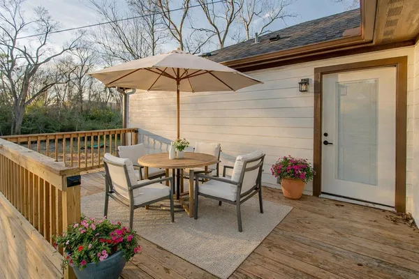 a view of a chairs and table on the wooden roof deck