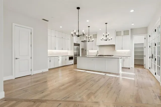 a large kitchen with kitchen island a stove a sink dishwasher and white cabinets with wooden floor