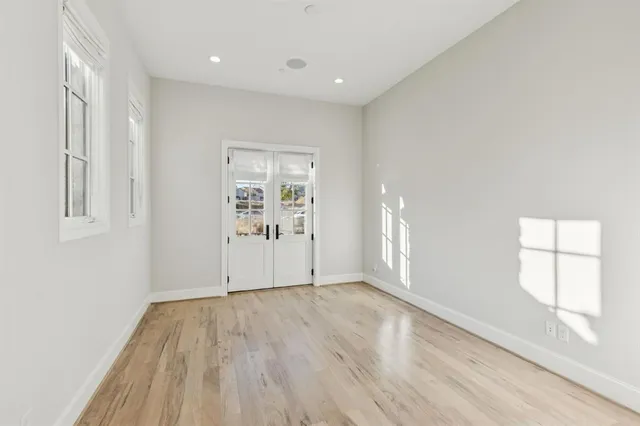 a view of an empty room with a window and wooden floor