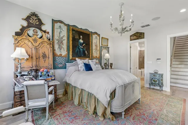 a bedroom with a large bed a chandelier and dresser