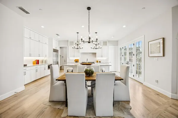 a view of a dining room and livingroom with furniture wooden floor kitchen view and a chandelier