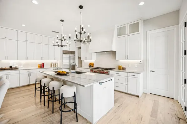 a kitchen with stainless steel appliances a white table chairs and a stove