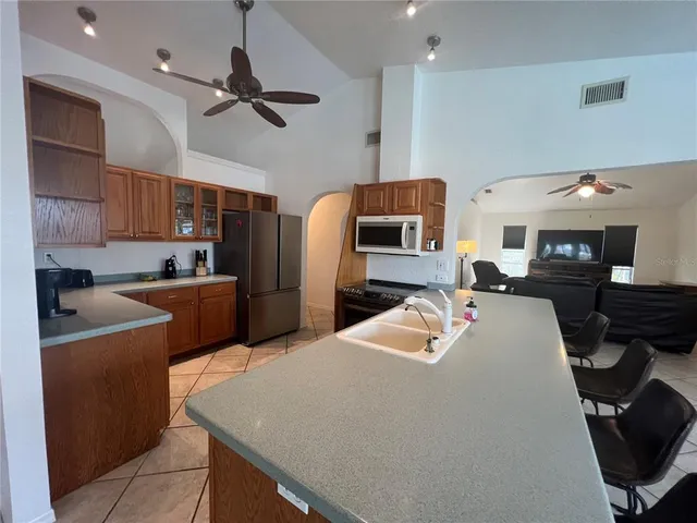 a kitchen with stainless steel appliances kitchen island granite countertop a sink dishwasher stove and refrigerator with wooden floor