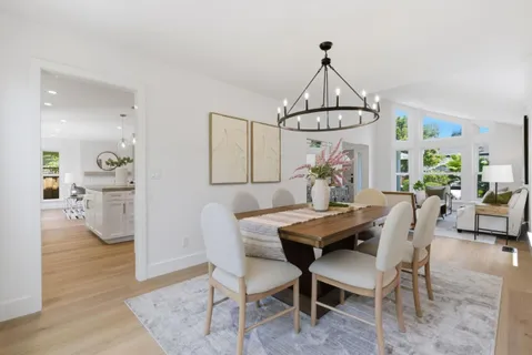 a dining room with wooden floor a chandelier a wooden table and chairs