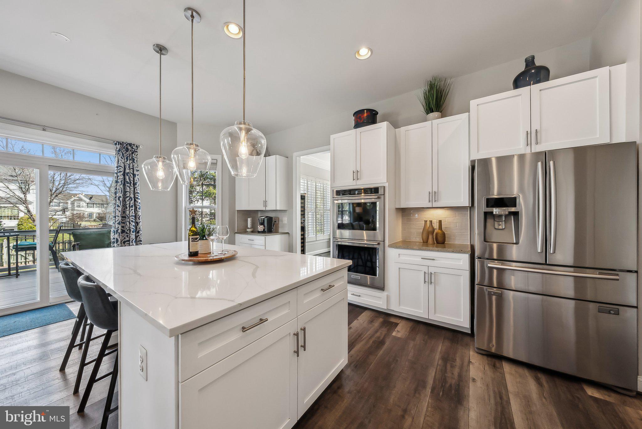 9061 Roaring Spring Loop Bristow, VA 20136 - Photo 14 of 55 a kitchen with white cabinets and stainless steel appliances