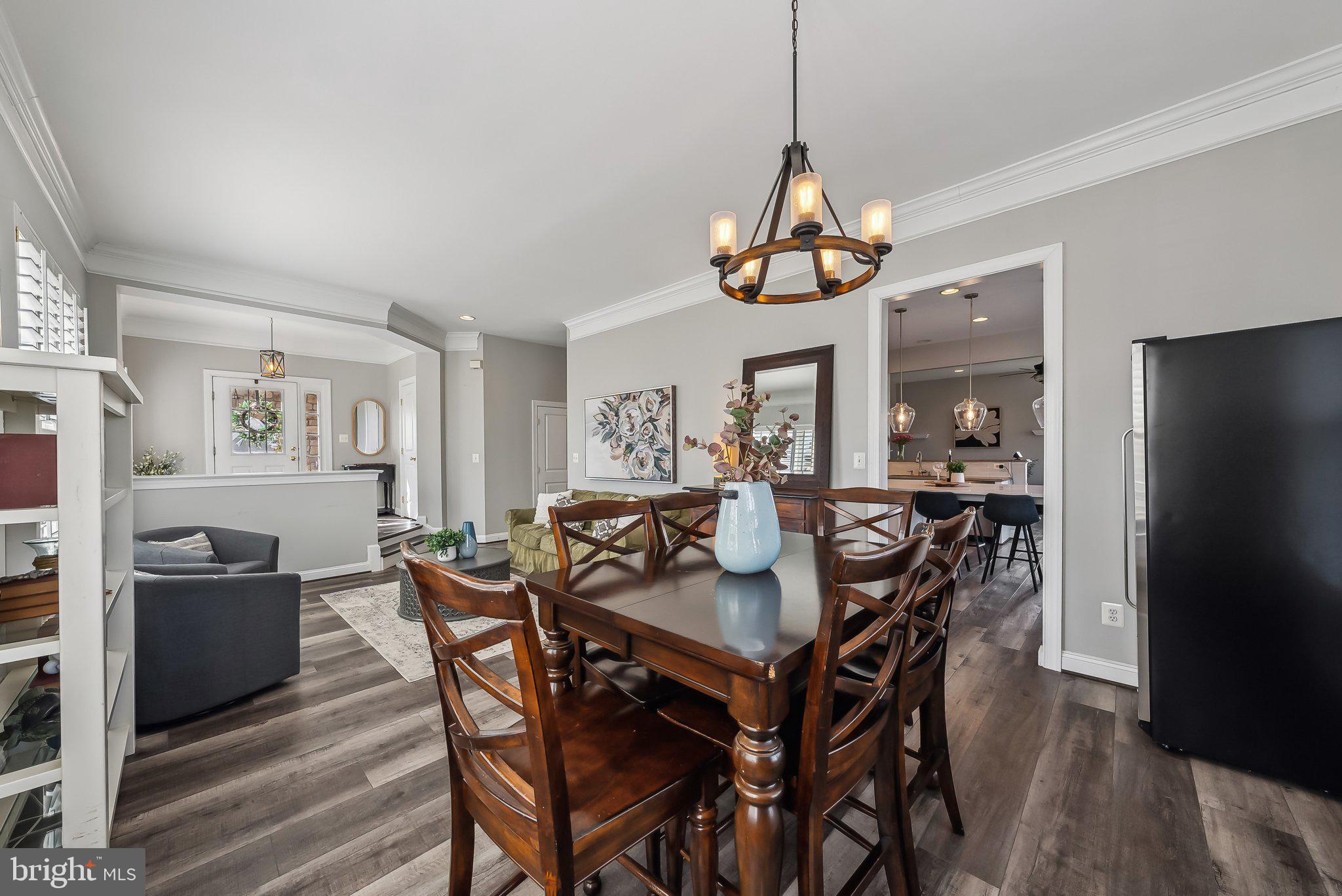 9061 Roaring Spring Loop Bristow, VA 20136 - Photo 7 of 55 a dining room with wooden floor a chandelier a wooden table and chairs