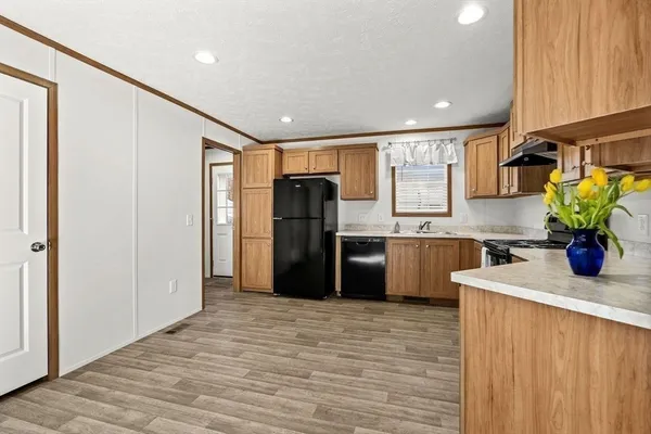 a kitchen with stainless steel appliances granite countertop a refrigerator a sink a stove and a wooden floors