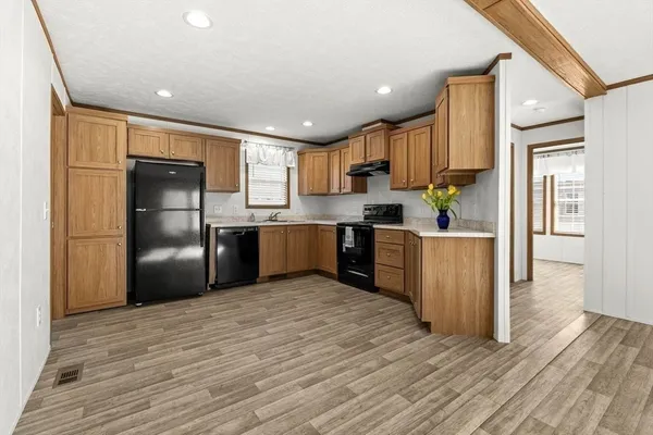 a kitchen with stainless steel appliances granite countertop a refrigerator a sink dishwasher and a oven with wooden floor