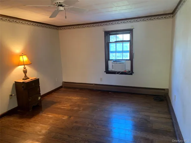 a view of an empty room with a window and wooden floor