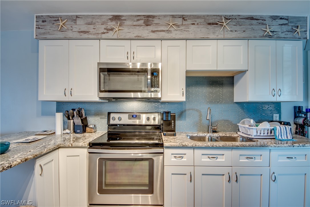 3215 Stringfellow Road, Unit 2D St. James City, FL 33956 - Photo 9 of 39 a kitchen with stainless steel appliances granite countertop a stove a microwave and cabinets