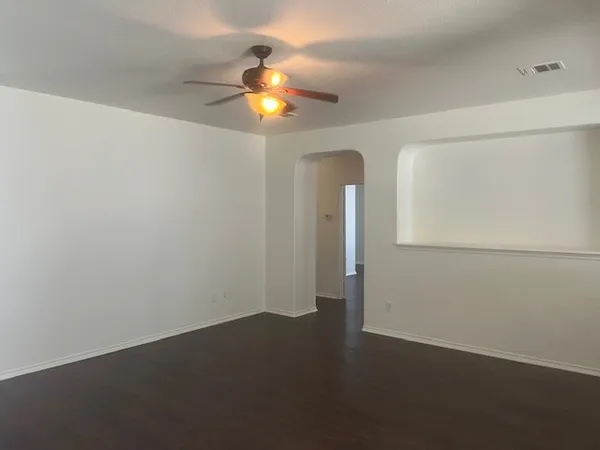 an empty room with wooden floor fan and window