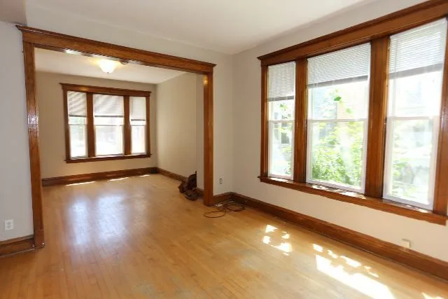 a view of an empty room with a window and wooden floor