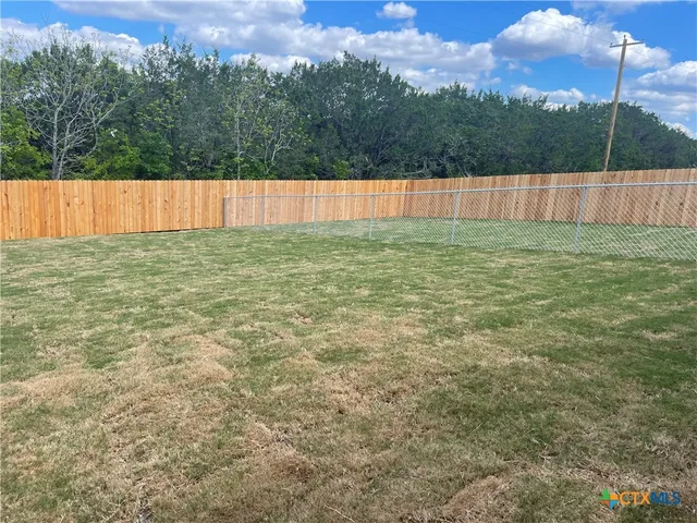 a view of a backyard with wooden fence