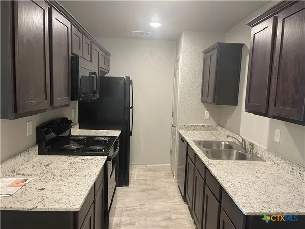 a kitchen with granite countertop a sink stove and refrigerator
