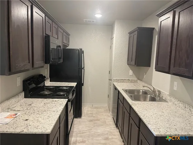 a kitchen with granite countertop a sink stove and refrigerator