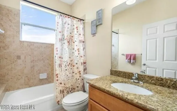 a bathroom with a granite countertop sink toilet mirror and shower