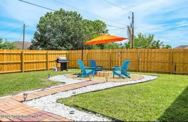 a view of a backyard with table and chairs under an umbrella