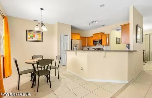 a dining hall with stainless steel appliances granite countertop a dining table chairs and a refrigerator