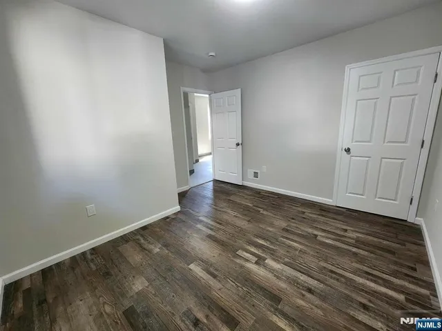 a view of an empty room with wooden floor and closet