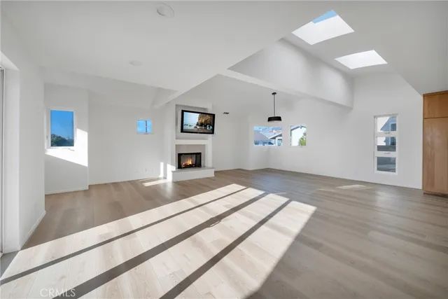 a kitchen with stainless steel appliances granite countertop a stove top oven a sink dishwasher and white cabinets with wooden floor