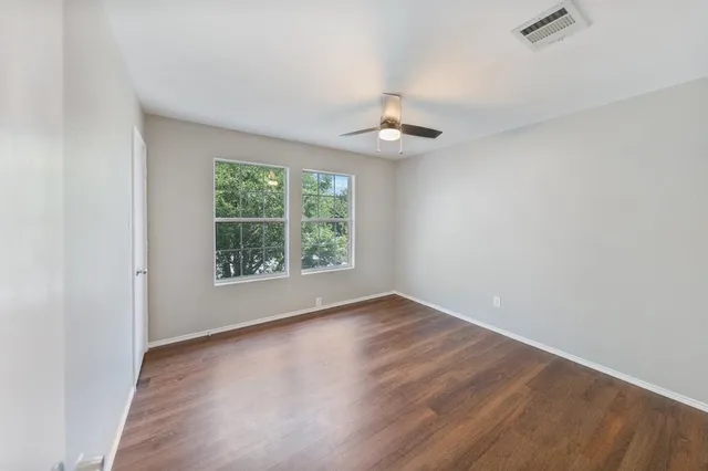 an empty room with wooden floor and windows