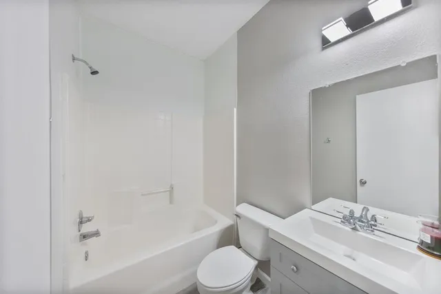 a bathroom with a bathtub shower sink vanity mirror and toilet