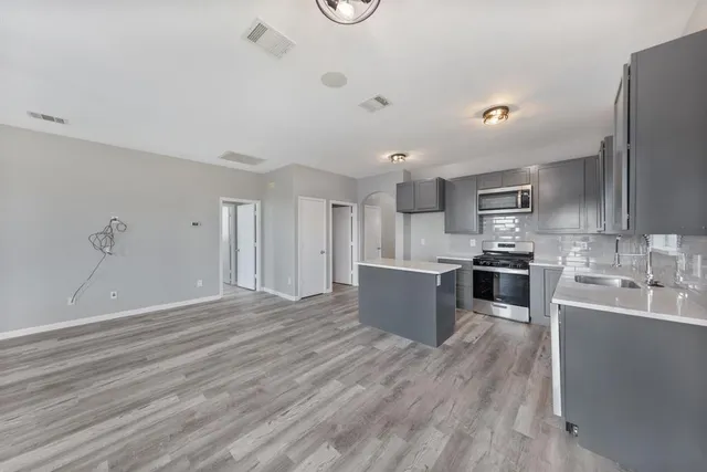 a large kitchen with stainless steel appliances granite countertop a lot of counter space and wooden floors