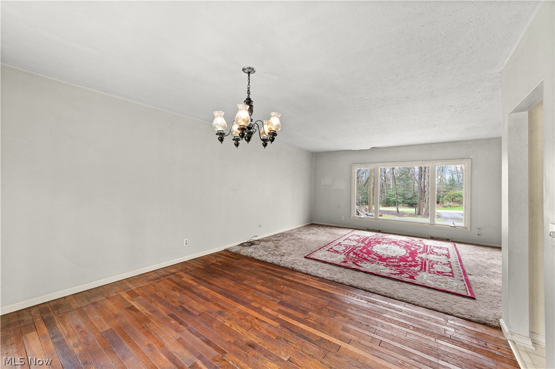 18763 Sharon Road Chagrin Falls, OH 44023 - Photo 19 of 37 Unfurnished room with hardwood / wood-style floors, a textured ceiling, and a chandelier