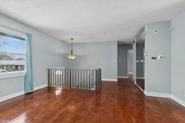 a view of a hallway with wooden floor and a bathroom