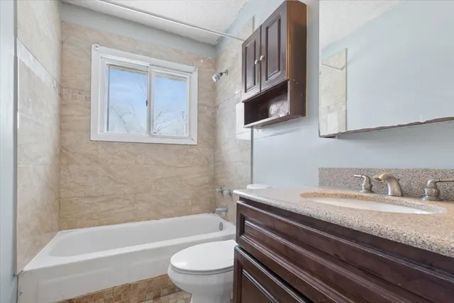 a bathroom with a granite countertop sink a toilet and bathtub