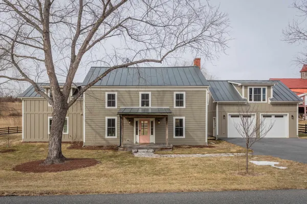 a front view of a house with a yard and large tree