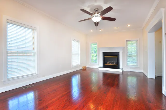 an empty room with wooden floor fireplace and windows
