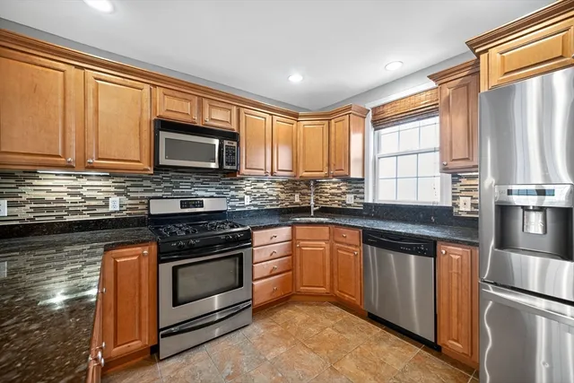 a kitchen with stainless steel appliances granite countertop wooden cabinets a stove a sink and dishwasher