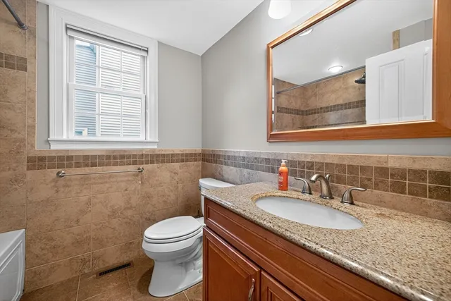a bathroom with a granite countertop sink toilet and mirror