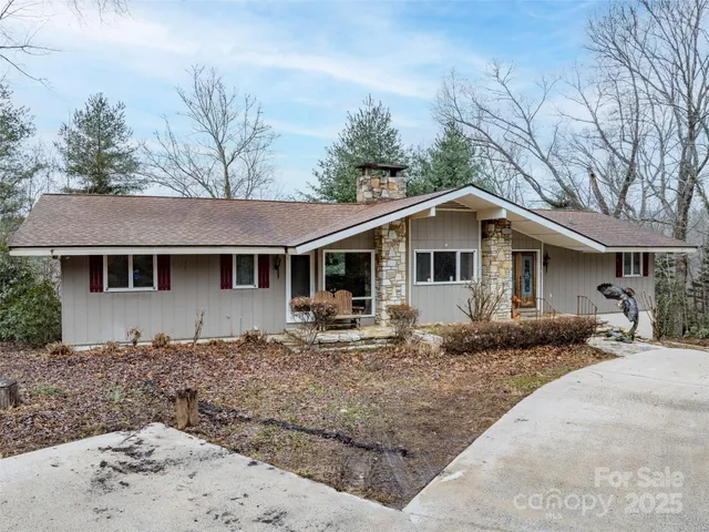 a front view of a house with yard and trees in the background