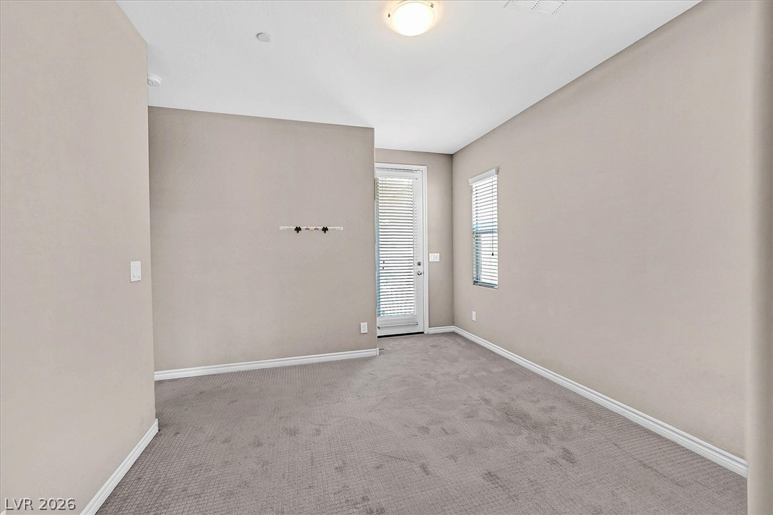 1106 Langston Ranch Avenue Henderson, NV 89002 - Photo 31 of 36 A well-lit, neutral-toned room features soft carpeting and natural light from a window and glass door.