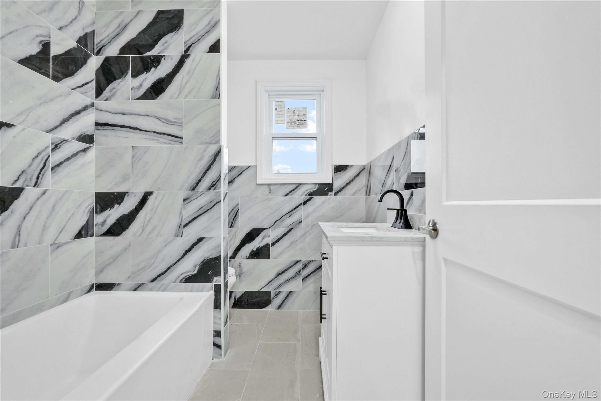 21432 112th Road Queens, NY 11429 - Photo 13 of 18 Full bathroom with vanity, tile walls, and wainscoting