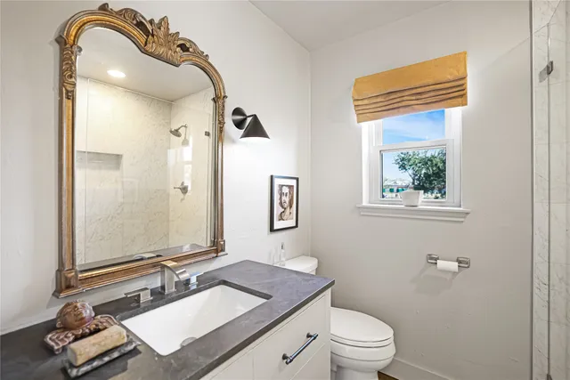 a bathroom with a granite countertop sink toilet and mirror