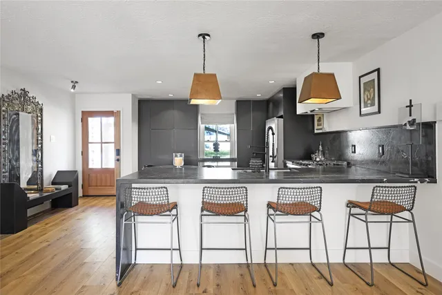 a kitchen with stainless steel appliances granite countertop a stove top oven a refrigerator a sink and chairs