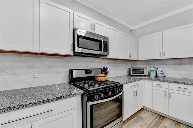 a kitchen with stainless steel appliances granite countertop grey cabinets a stove a sink and dishwasher