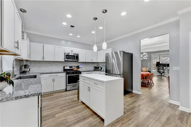 a kitchen with a refrigerator a sink dishwasher and a stove with wooden floor